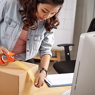 Online-Unternehmer verwendet Klebeband zum Verpacken von Paketen im Home Office